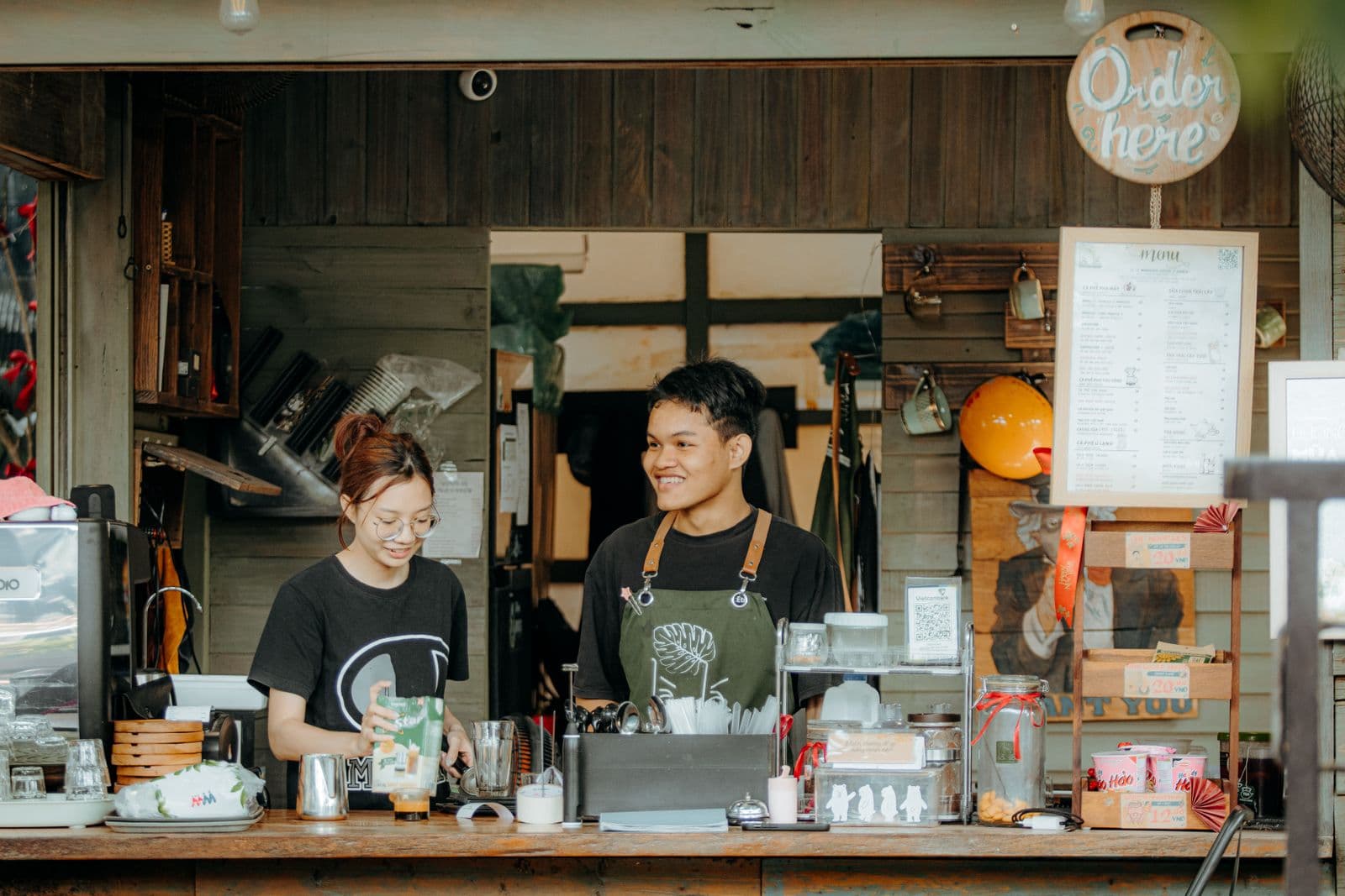 Δύο barista χαμογελούν πίσω από τον πάγκο ενός καφέ